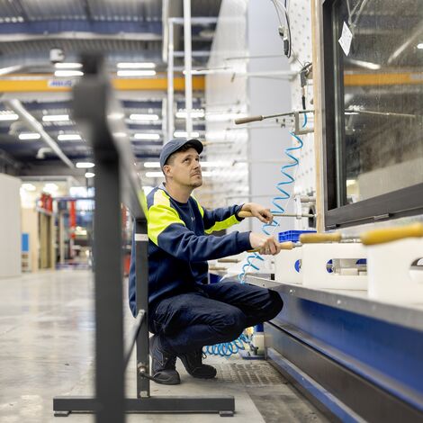 Oficer testowy klęczący podczas testu AWW na OKNO w kampusie reynaers.