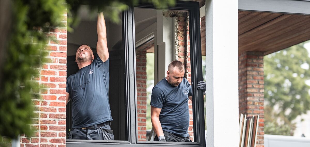Dwóch instalatorów umieszcza nowy profil aluminiowy w odnowionym domu.