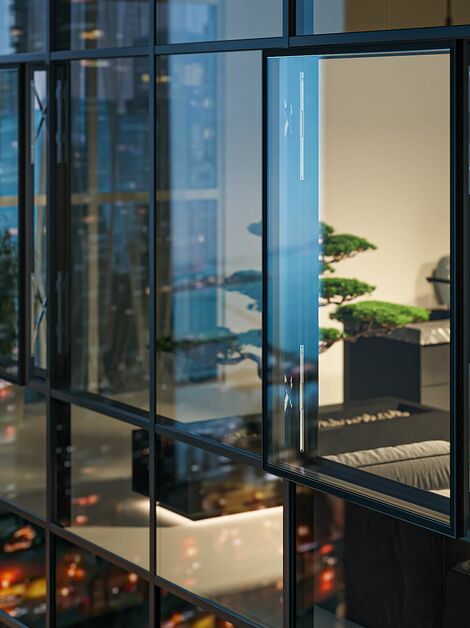 Night view of a high-rise building with an open parallel window in the glass façade.