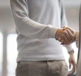 Mężczyzna i kobieta ściskają sobie dłonie w budynku biurowym.